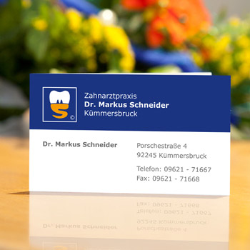 Visitenkarte „Dr. Markus Schneider“ in Blau und Weiß ist auf der Rezeptionstheke aufgestellt